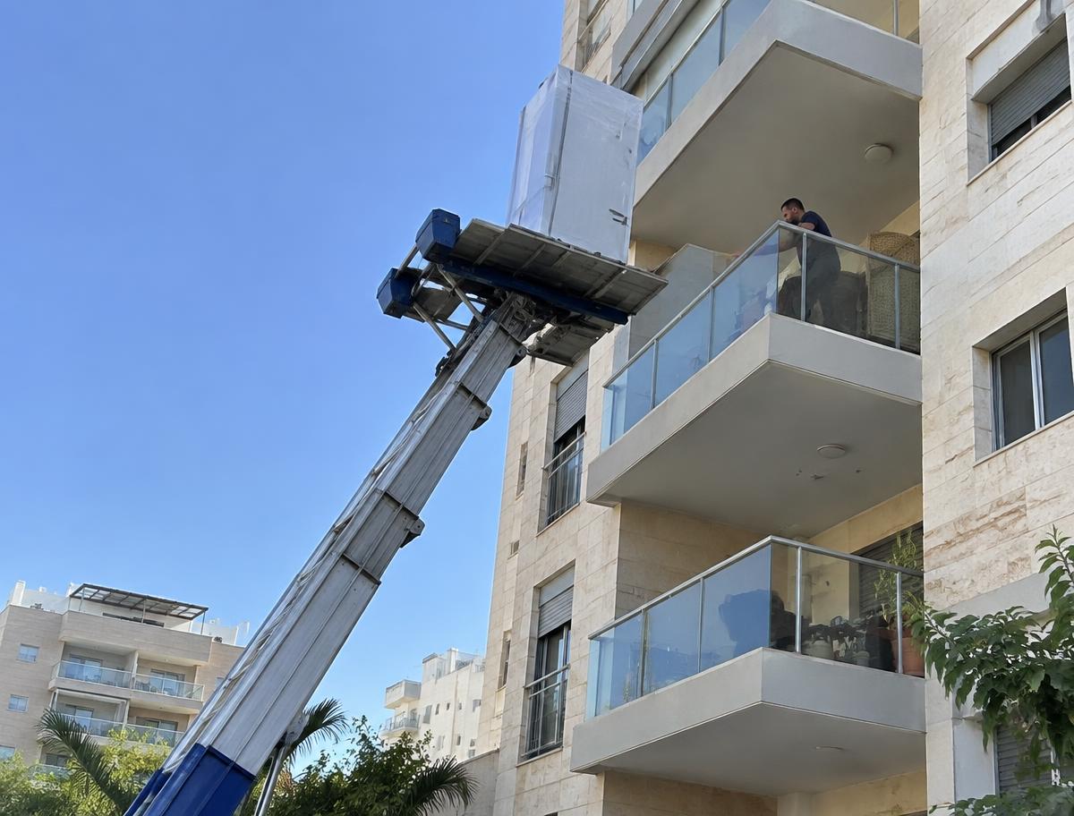 מנוף הרמה מעלה מקרר עטוף למרפסת בבניין מגורים